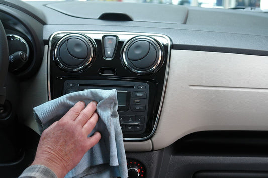 Hand trocknet das Armaturenbrett mit einem Mikrofasertuch nach der Autowäsche.