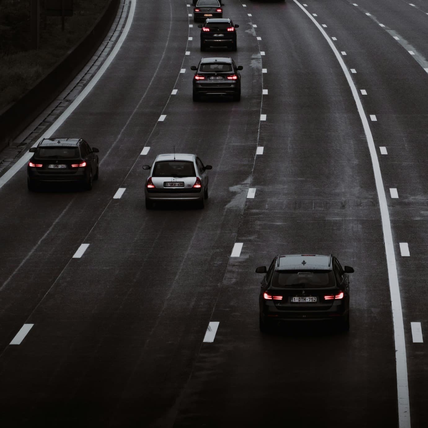 Autobahnverkehr mit mehreren Autos auf nasser mehrspuriger Straße.