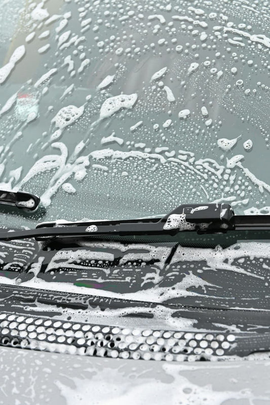 Autowindschutzscheibe wird mit Seife für ein streifenfreies Ergebnis gewaschen.