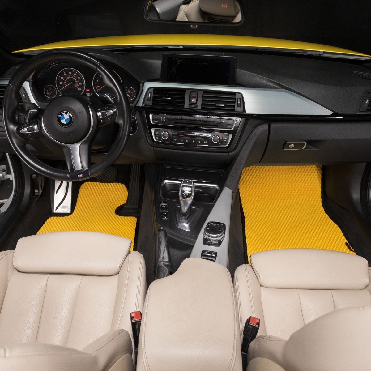 Gelbe EVA-Autobodenmatten mit beigem Lederinterieur in einem BMW Innenraum.