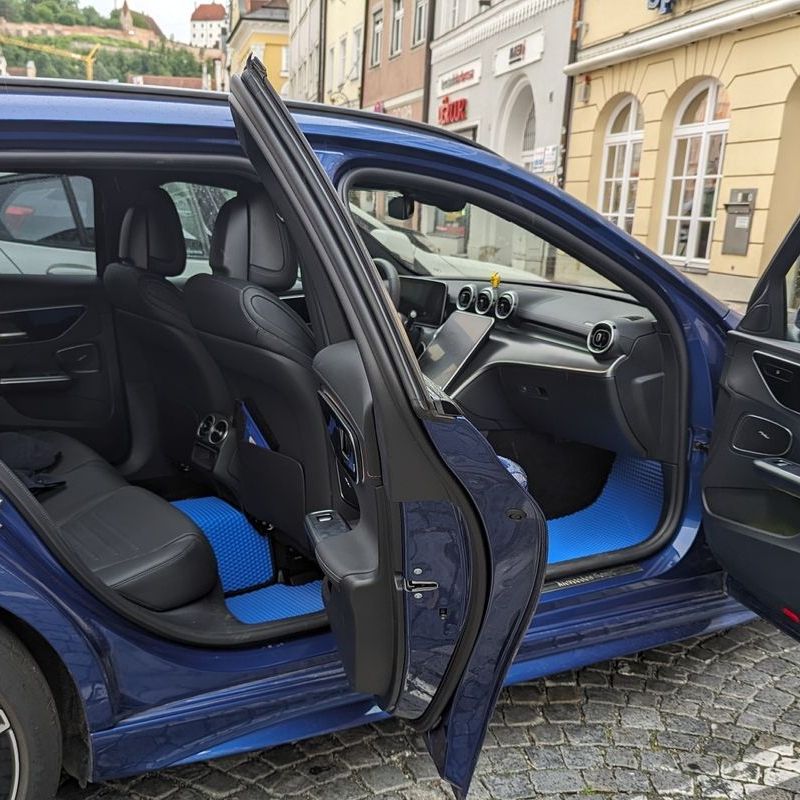 Blauer EVA-Autozubehör-Matte im Innenraum eines Fahrzeugs mit grauen Ledersitzen.