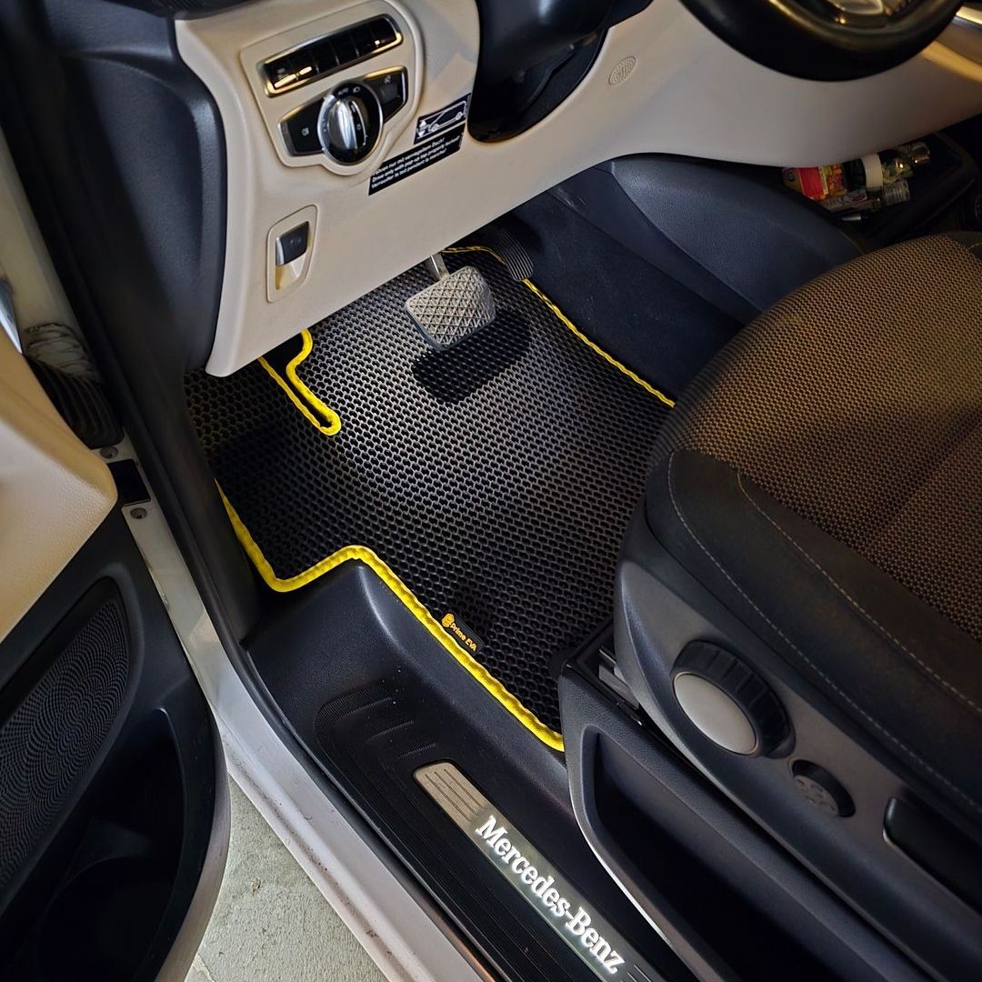 Schwarzer EVA-Autoteppich mit gelbem Rand im Mercedes-Benz Innenraum.