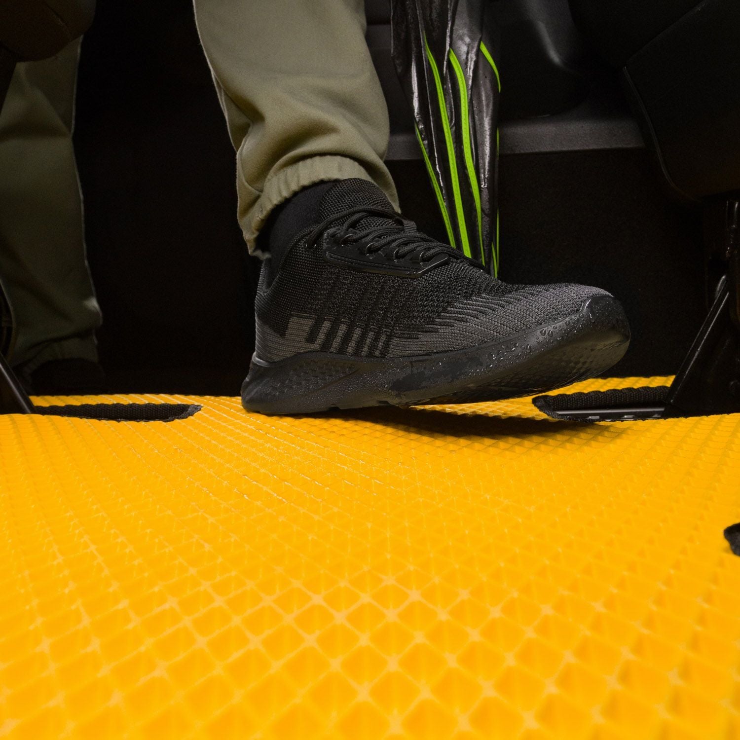 Schwarzes Sport Schuh auf einer rutschfesten, gelben EVA-Autofußmatte mit strukturiertem Design.