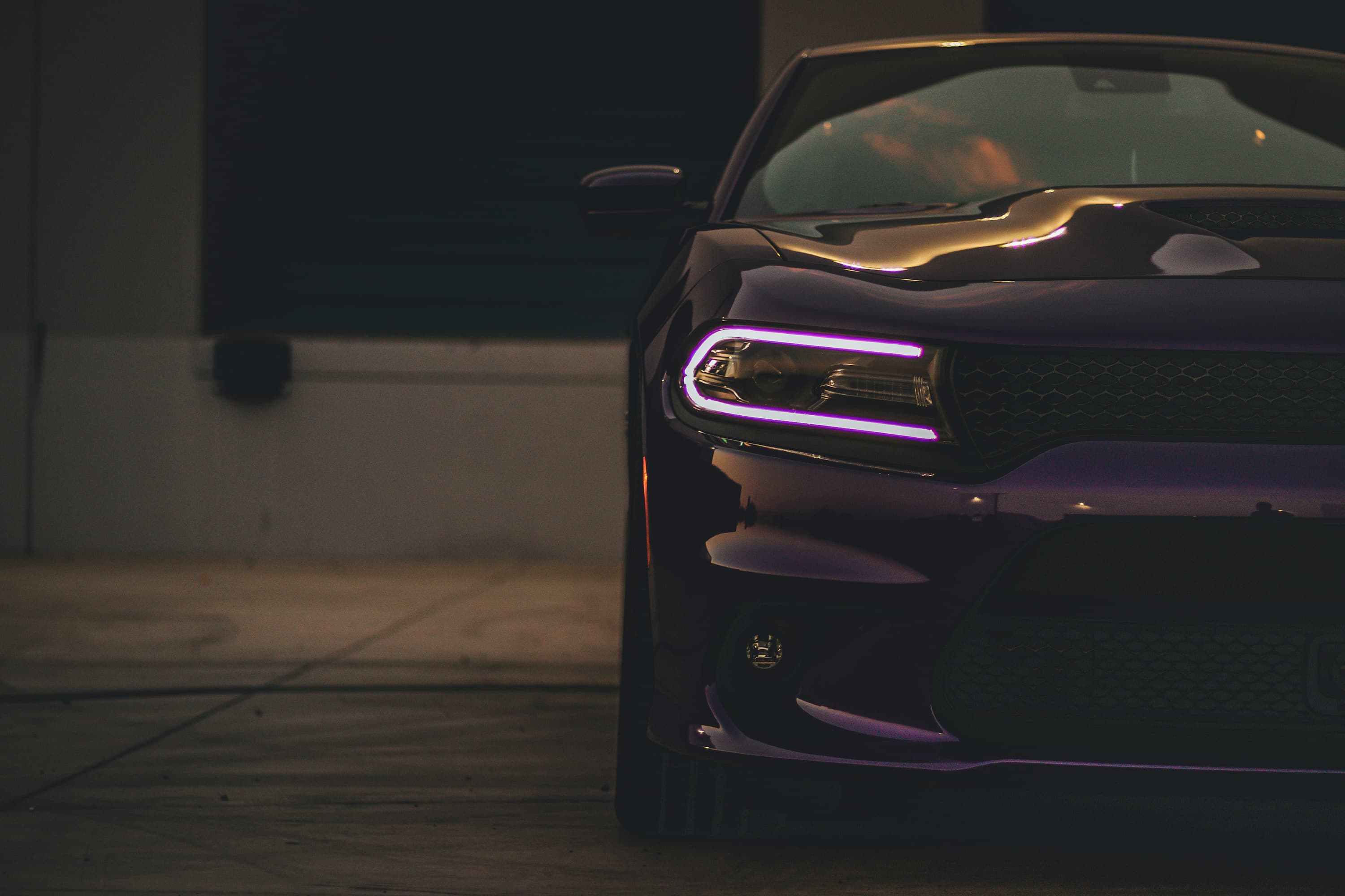 Vorderansicht eines dunkelvioletten Autos mit modernen LED-Scheinwerfern in dunkler Umgebung.
