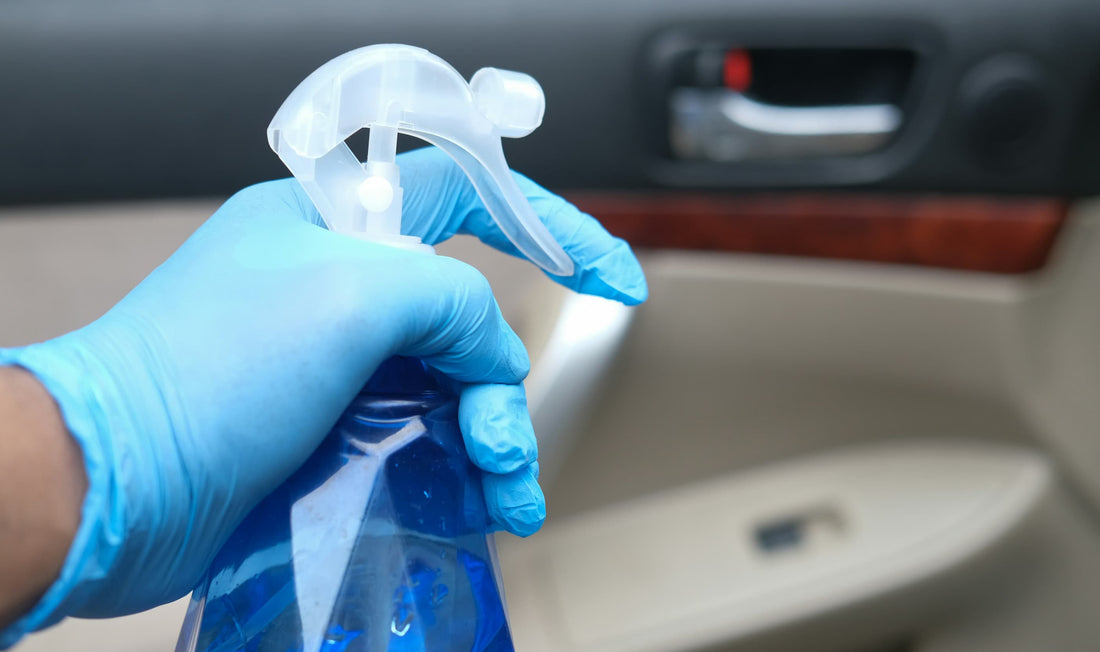 Reinigung der Autotür im Innenraum mit Desinfektionsspray und Handschuhen.