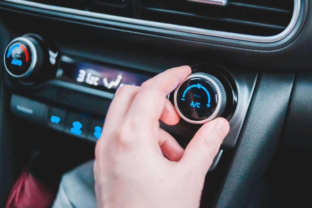 Hand stellt den Regler der Auto-Klimaanlage ein.