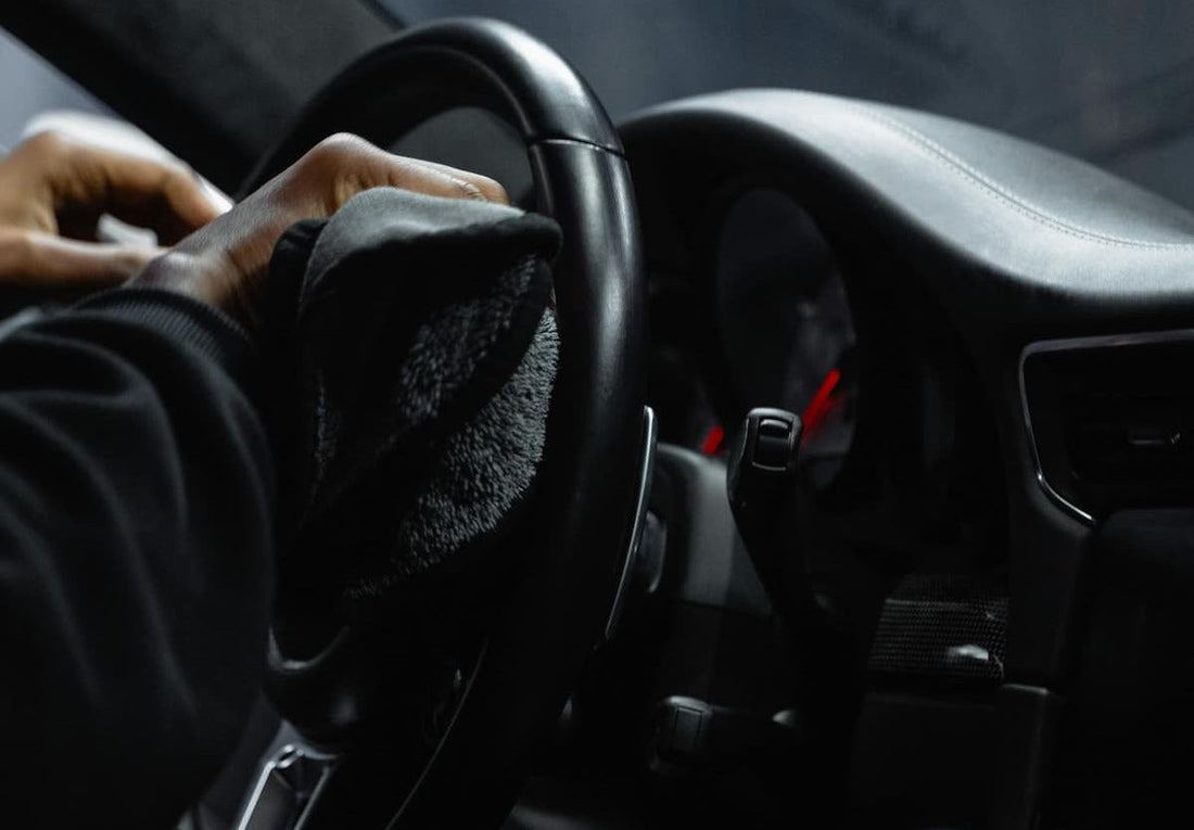 Reinigung eines Auto Lenkrads mit Tuch im Innenraum für Hygiene und Pflege.