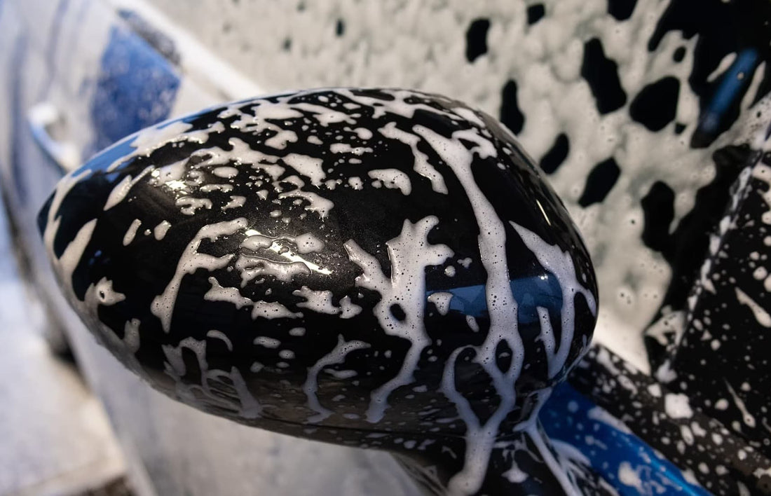 Seitenspiegel des Autos mit Schaum bedeckt während einer gründlichen Autowäsche.