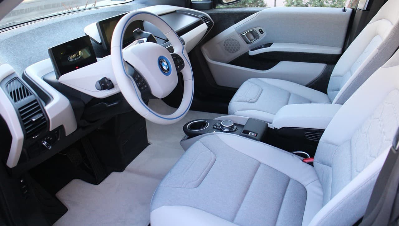 Modernes BMW-Interieur mit heller Polsterung und zwei Bildschirmen auf dem Armaturenbrett.