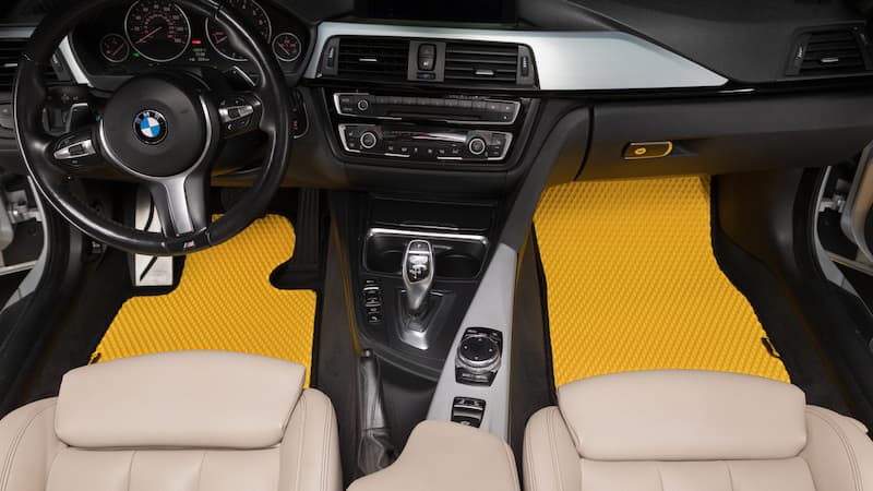 Gelbe Prime EVA Fußmatten im vorderen BMW-Innenraum.
