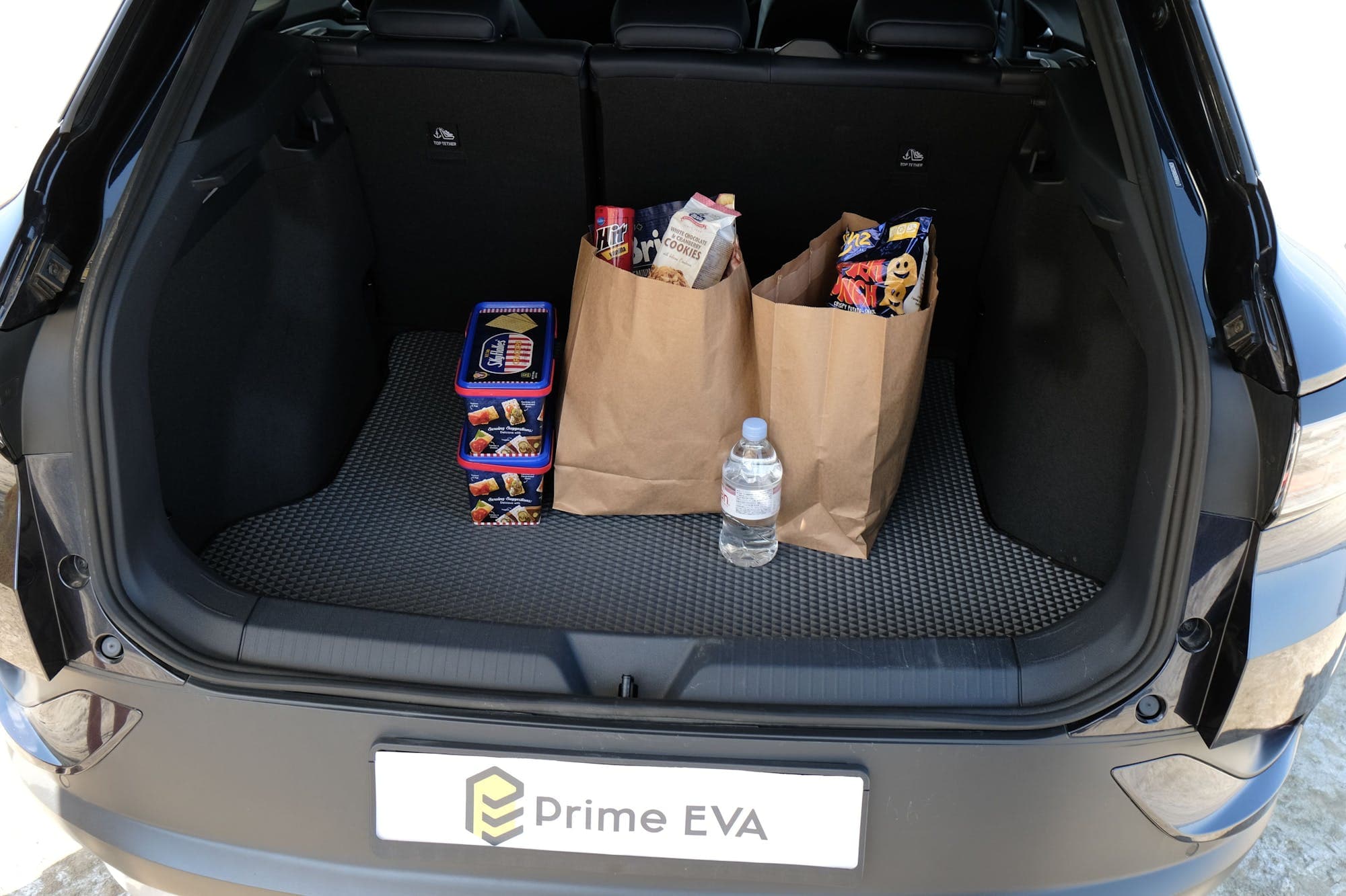 EVA-Kofferraummatte mit Einkaufstüten und Wasserflasche im Kofferraum.