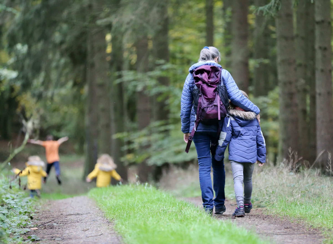 Familie wandert gemeinsam auf einem Waldweg.
