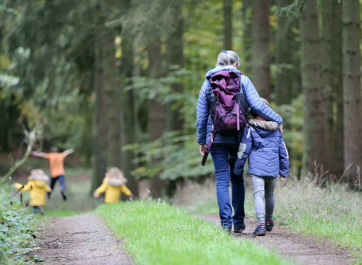 Familie wandert gemeinsam auf einem Waldweg.
