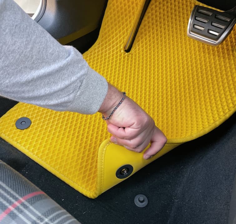 Hand befestigt gelbe EVA Fußmatte mit Clip im Fahrerbereich.