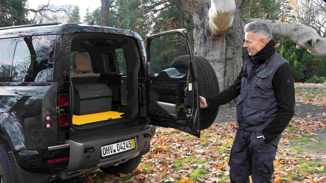 Mann öffnet einen SUV-Kofferraum mit gelber Prime EVA Kofferraummatte.