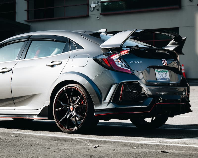 Grauer Honda Civic Type R mit Heckspoiler im Freien geparkt.