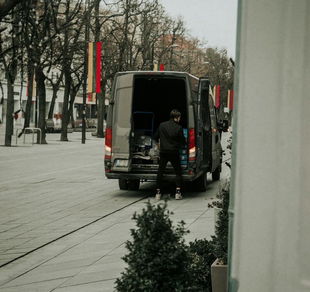 Lieferfahrer entlädt Pakete aus einem Transporter auf einer Stadtstraße.