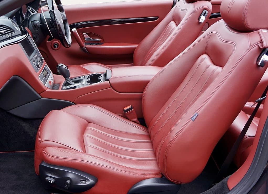 Luxuriöser roter Leder-Innenraum eines Autos mit Vordersitzen und Mittelkonsole.