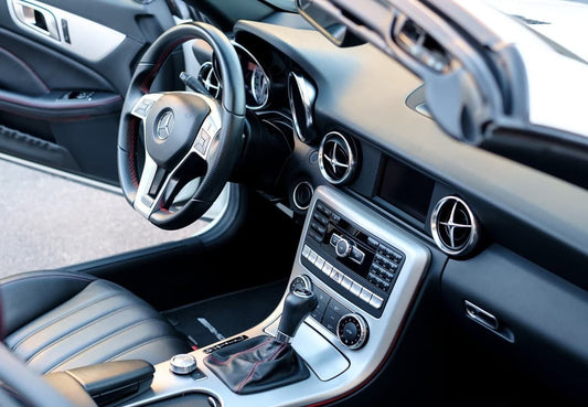 Nahaufnahme eines Luxusauto-Armaturenbretts mit Lederinterieur und verchromtem Lenkrad.