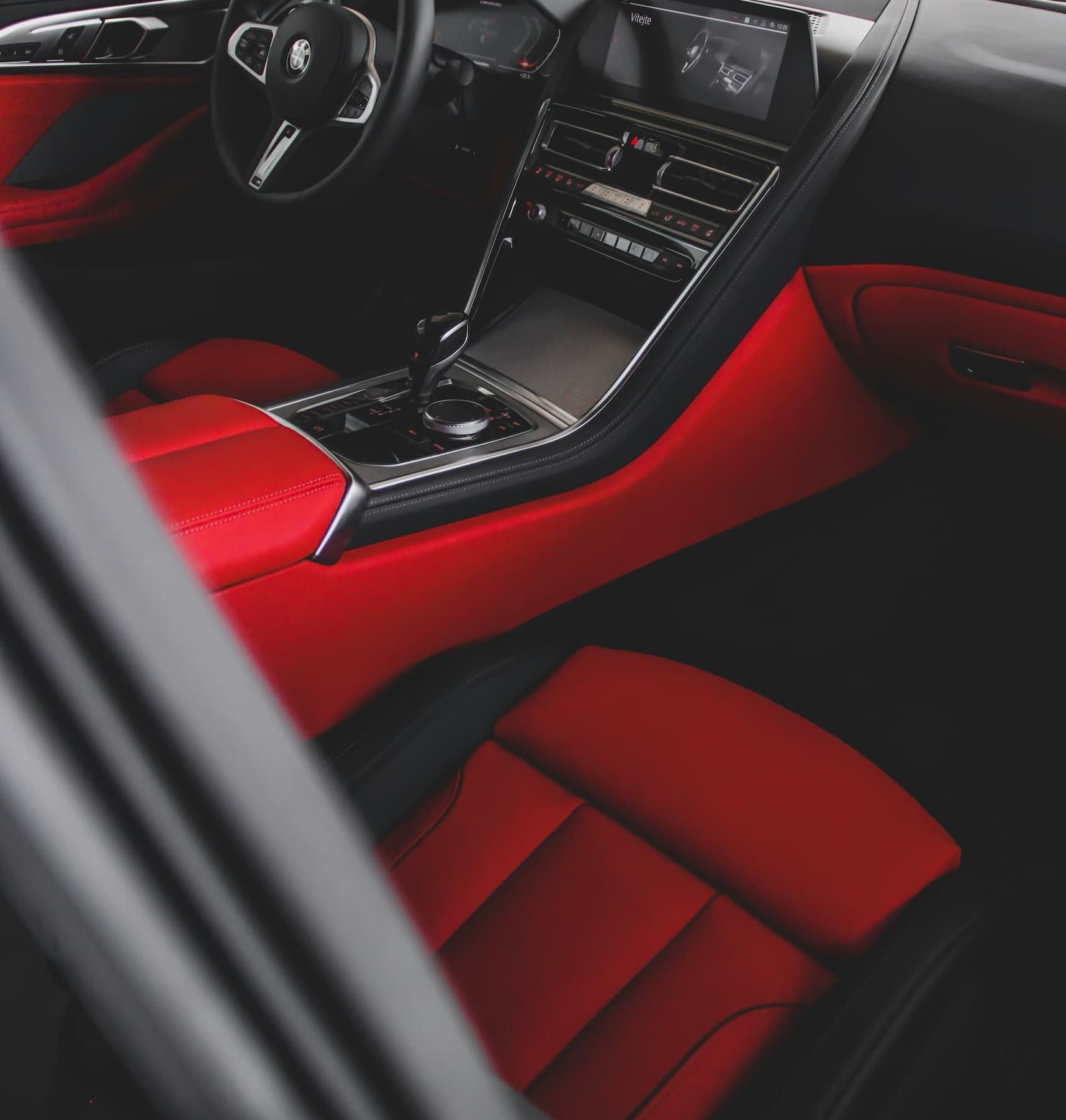 Nahaufnahme eines Luxusauto-Innenraums mit roten Ledersitzen und elegantem Armaturenbrett.