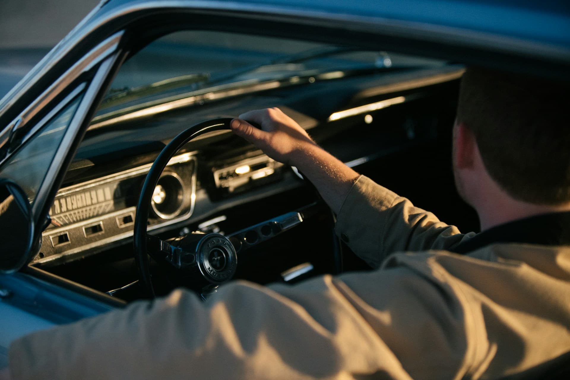 Mann am Steuer eines Oldtimers bei Sonnenuntergang.