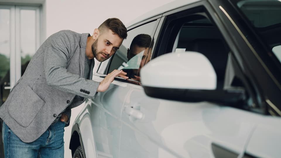 Mann prüft den Fahrzeugzustand im modernen Autohaus.