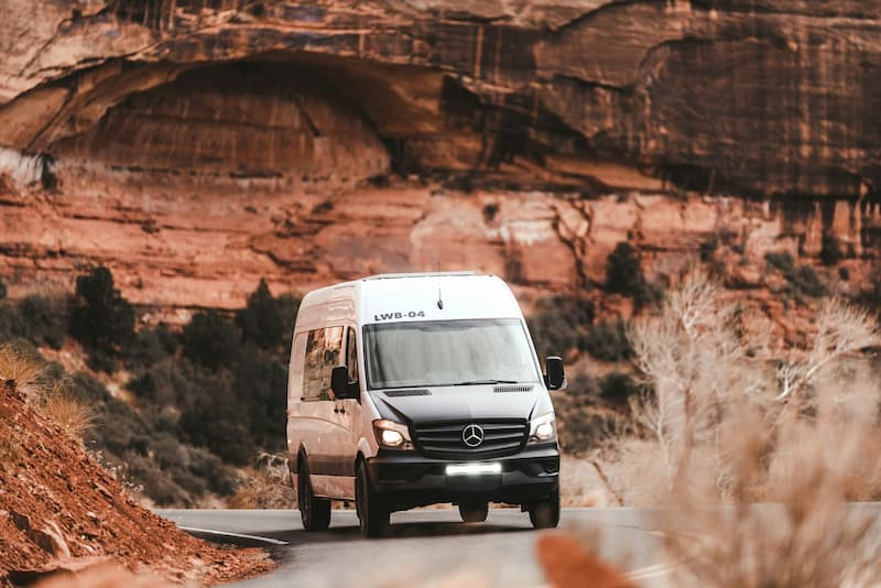 Mercedes Sprinter Kleinbus auf malerischer Straße.
