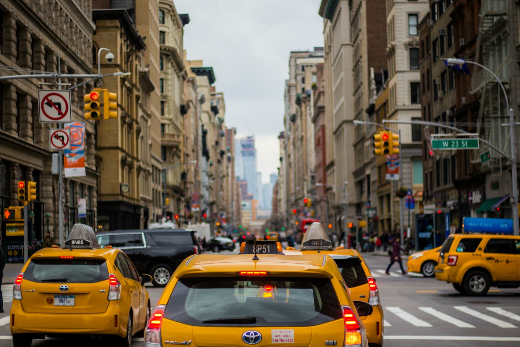 Gelbe Taxis fahren eine belebte Straße in New York City entlang, flankiert von hohen Gebäuden.