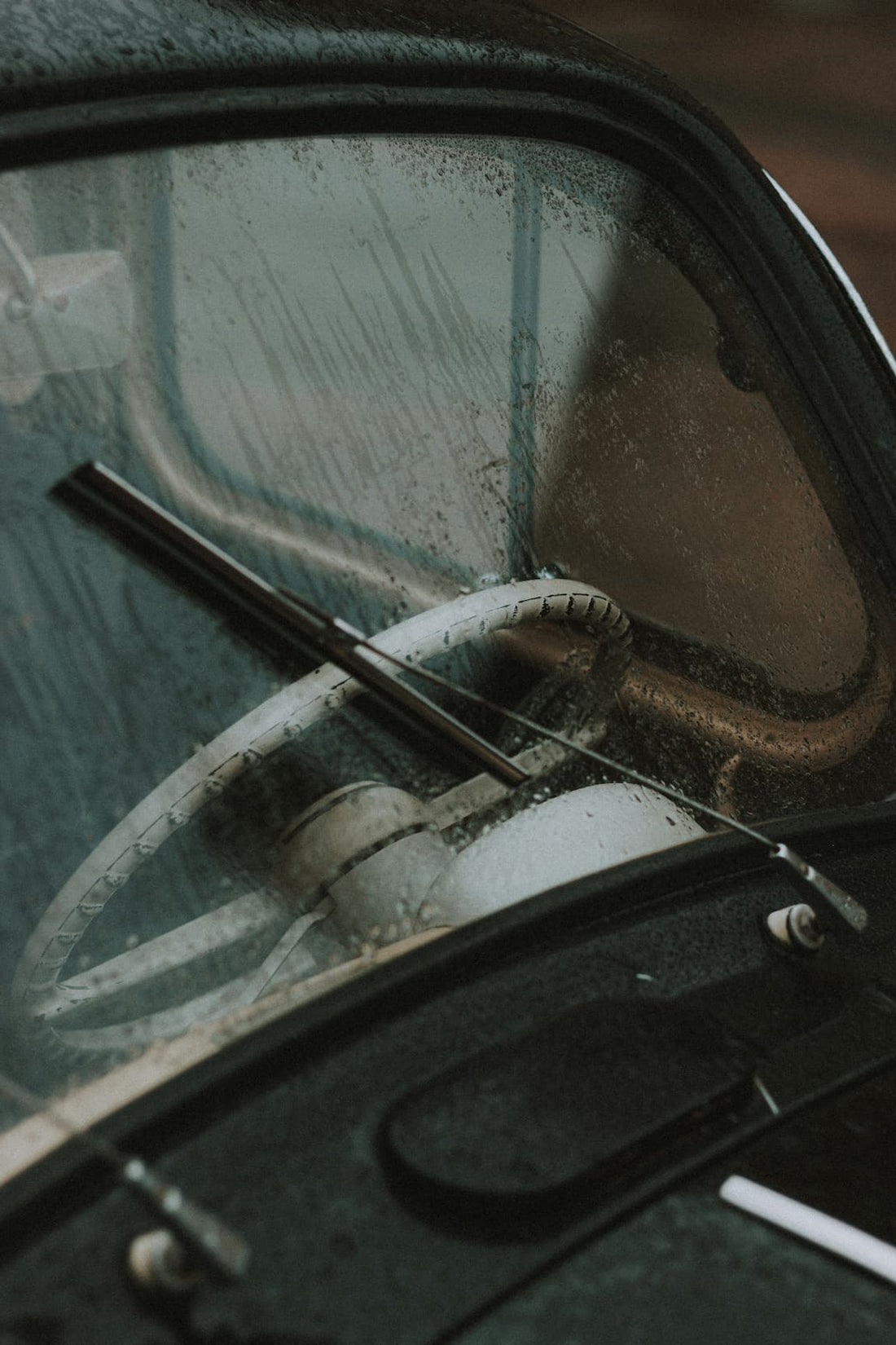 Oldtimer-Lenkrad durch regennasse Windschutzscheibe gesehen.