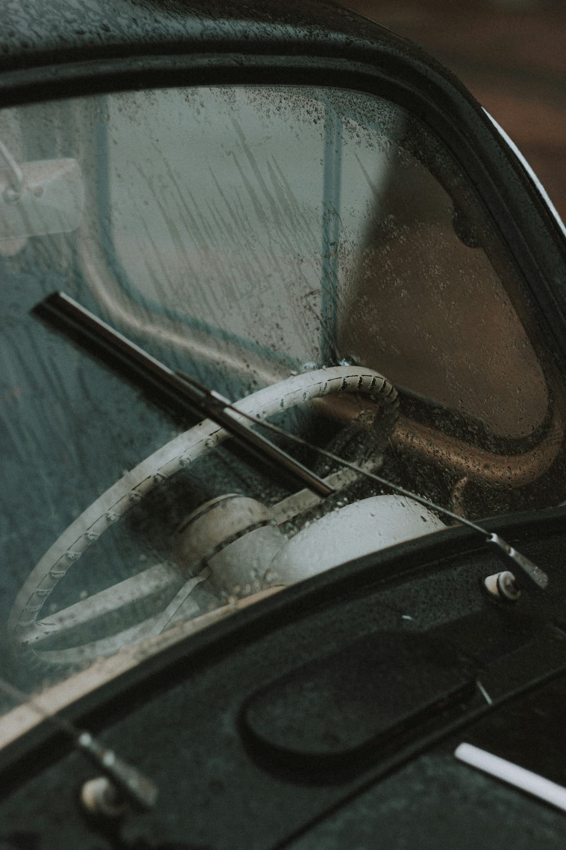 Oldtimer-Lenkrad durch regennasse Windschutzscheibe gesehen.