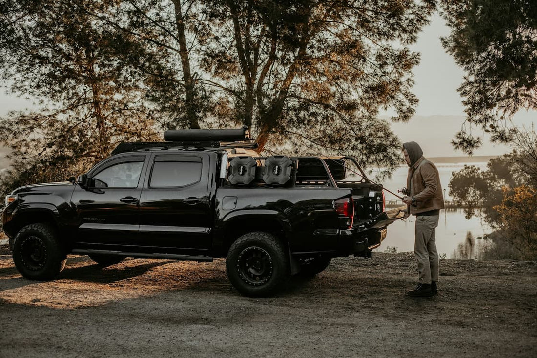 Pickup Truck fürs Overlanding am See, Mann organisiert Campingausrüstung.