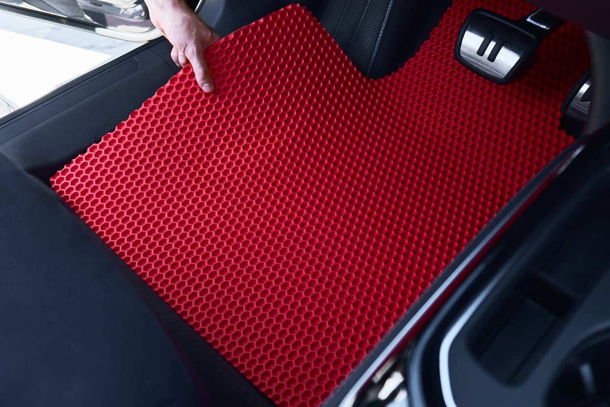 Rote EVA-Autofußmatte wird im Fahrzeug nahe der Pedale eingebaut.