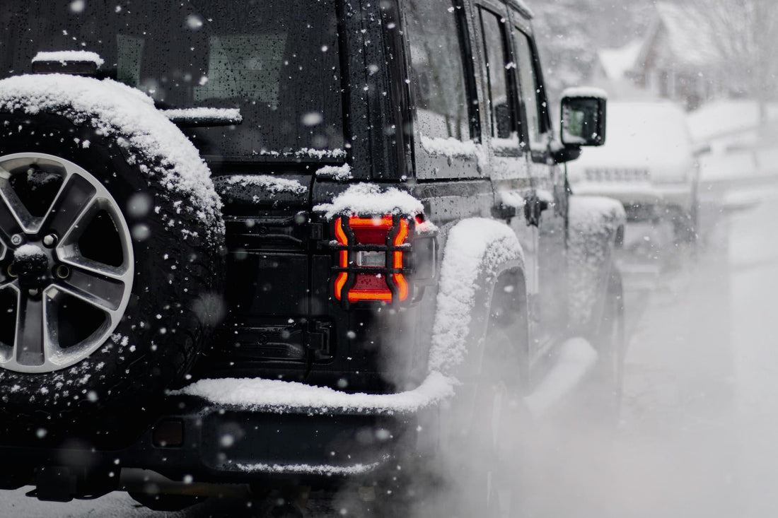 Schwarzer SUV fährt auf schneebedeckter Straße mit Schnee auf Reifen und leuchtendem Rücklicht.