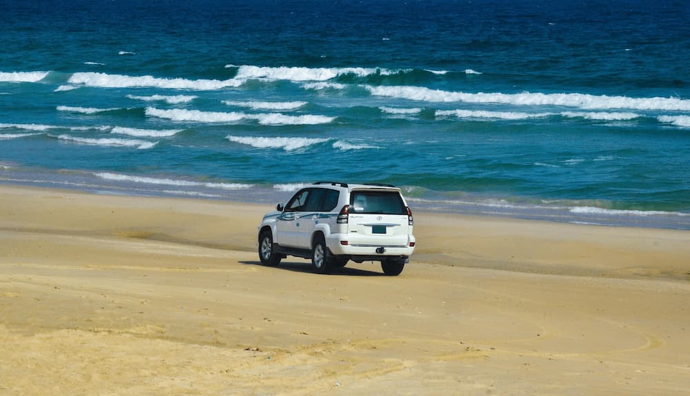 SUV fährt am sandigen Strand entlang und zeigt Abenteuer und Reisefreiheit.