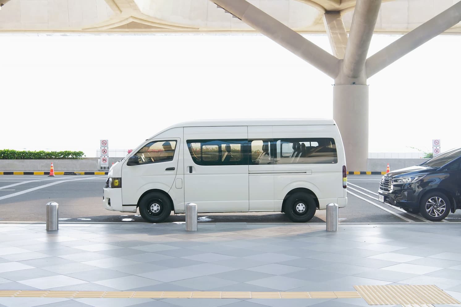 Weißer Kleinbus vor einem Flughafenterminal geparkt