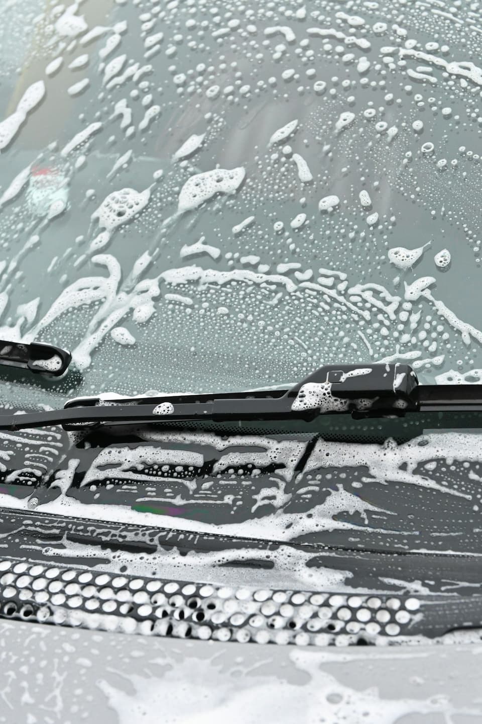 Autowindschutzscheibe wird mit Seife für ein streifenfreies Ergebnis gewaschen.