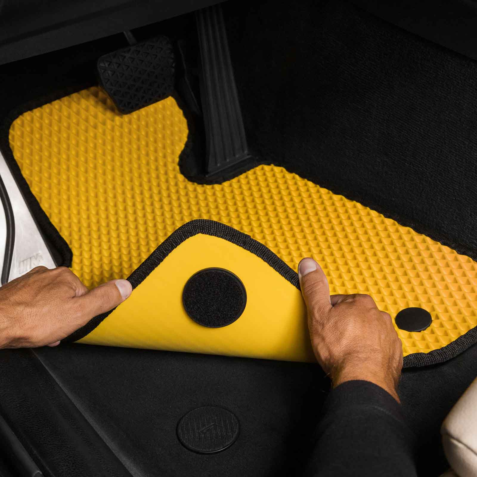Nahaufnahme einer spezialgelben Autofußmatte, die in ein BMW-Fahrzeug eingesetzt wird.