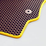 Dunkelviolette Matte mit gelbem Rand und Metallknopf in Wabenstruktur.
