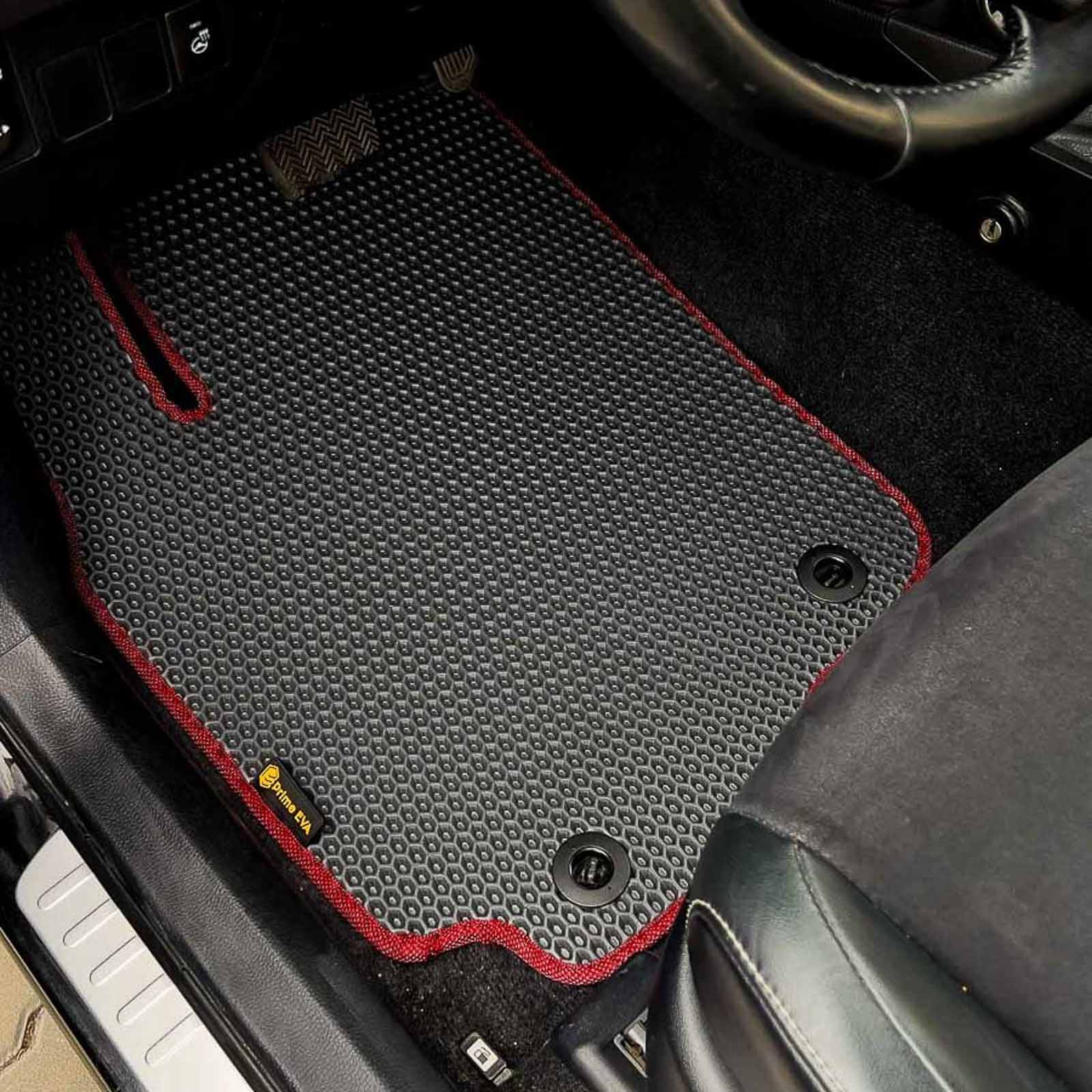 Nahaufnahme eines spezialgefertigten schwarzen Autoteppichs mit roter Naht im Innenraum eines Toyota RAV4.